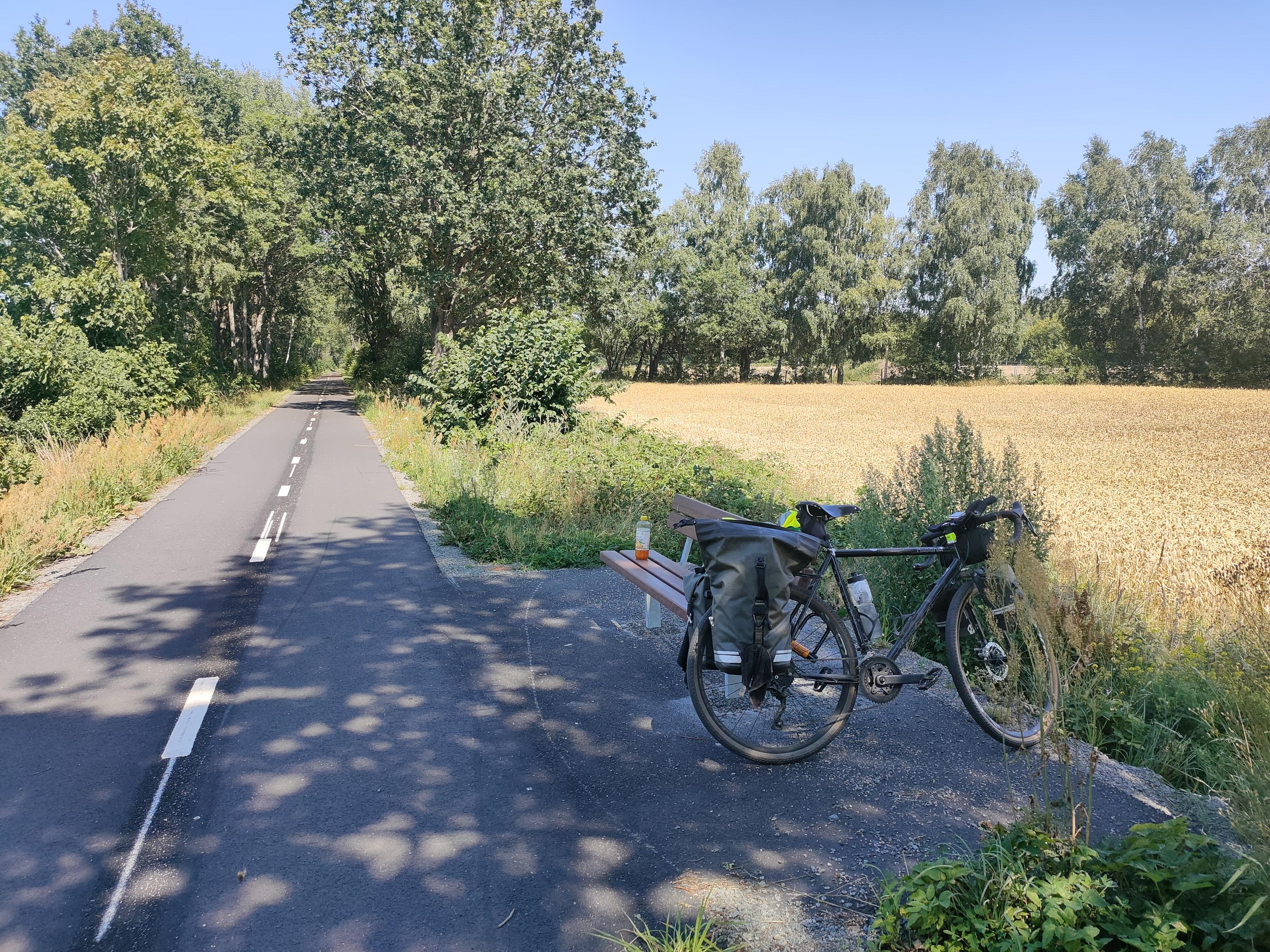 My bike next to a bench at the side of bike path.